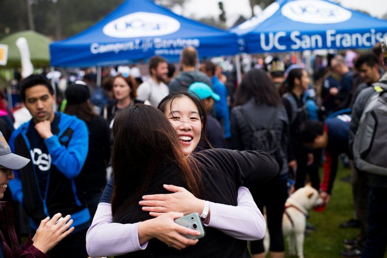 Women hugging at an outdoor event. 