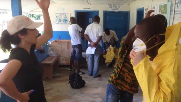 a UCSF responder to the Ebola outbreak teaches a man how to wear protective clothing