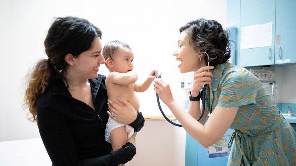 doctor holds up a stethoscope to an infant