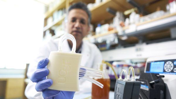 Shuvo Roy holds a prototype of the artificial kidney