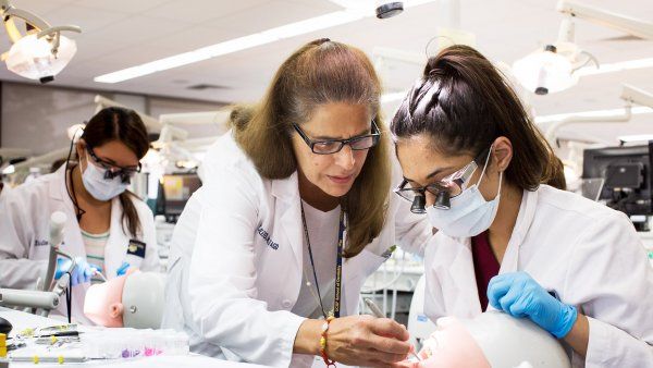 Dentistry professor instructs student in a simulation lab