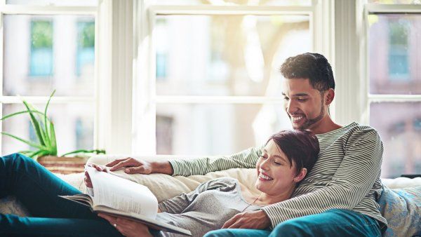 couple smiling while reading on a couch