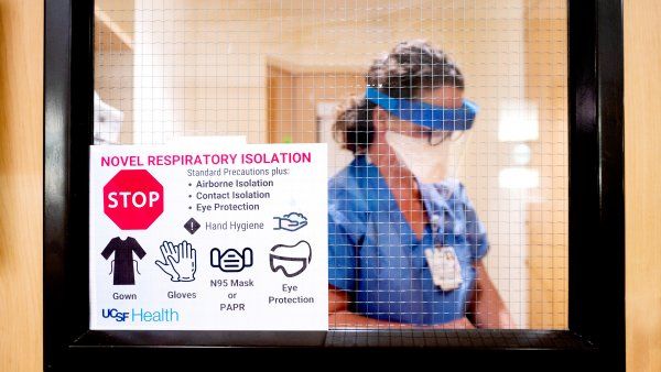 nurse dons protective equipement in an isolation room