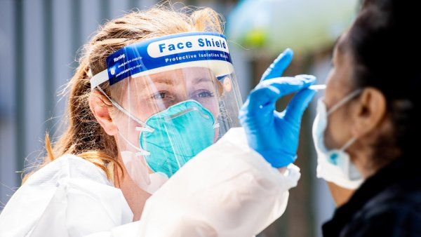 nurse administers a nasal swab for COVID-19 testing at a Mission District testing site