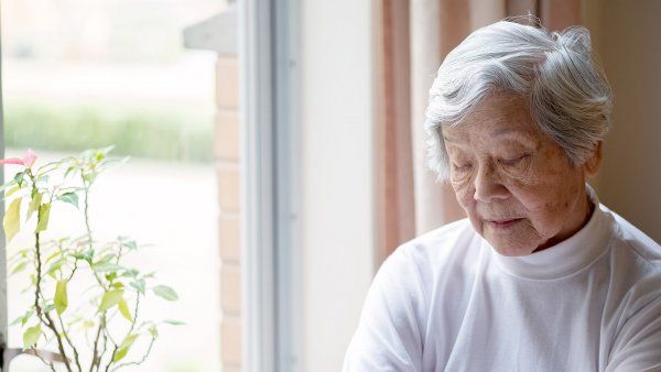 older woman sits by a window