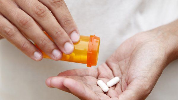 two pills pour from bottle into hand