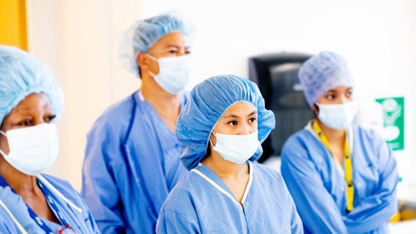 staff stand in gowns and masks