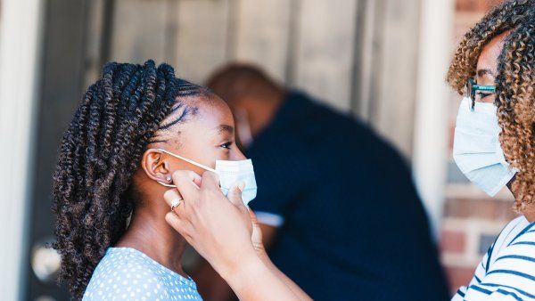 mother adjusts mask on young girl