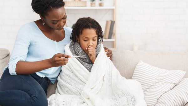 mother looks at thermometer with sick daughter