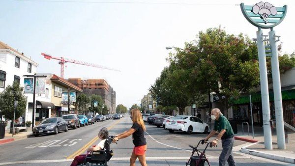 two people in wheelchairs are pushed across a street