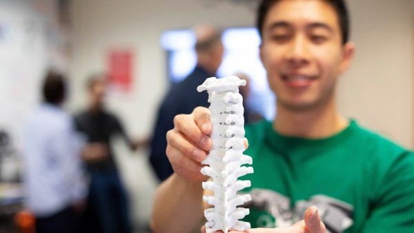 man holds a 3d-printed human spine model