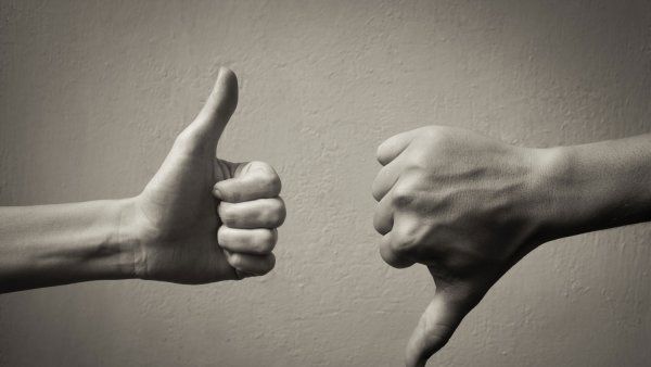 Black and white photo of one hand giving thumbs up, one hand giving thumbs down