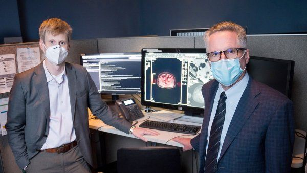 Tomas Hope and Peter Carroll stand in front of a computer with patient's scan on the screen