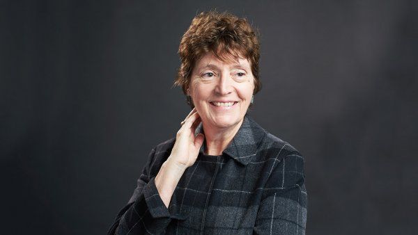 Portrait of Barbara Koenig in front of a black background.