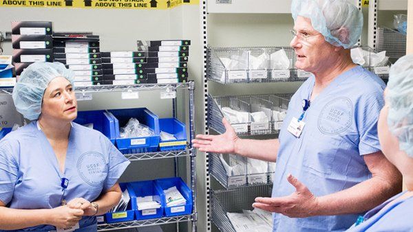 Photo of doctors in scrubs in a supply room in a hospital having a discussion.