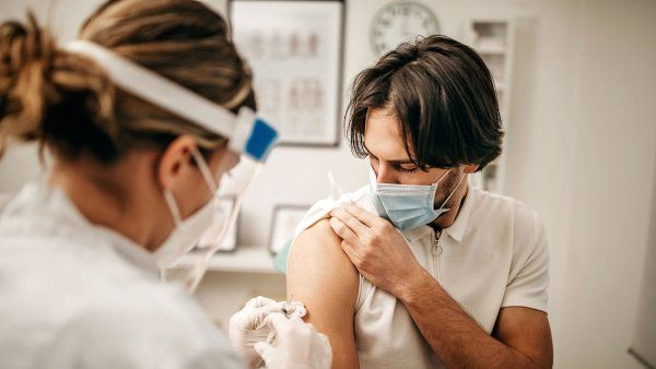 Young man wearing mask getting a shot in the arm