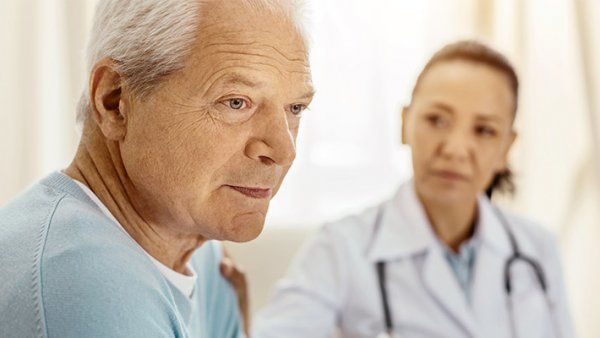 A doctor comforts an elderly man.