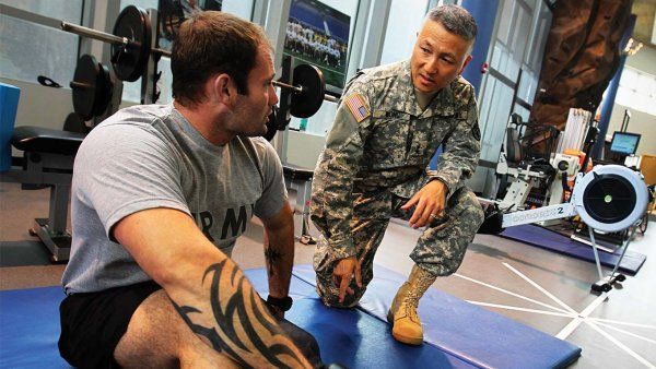 Major General Ted Wong, a School of Dentistry graduate, checks in with a patient using the Intrepid Dynamic Exoskeletal Orthosis – an indispensible rehabilitation technology developed at one of the medical centers under his command.