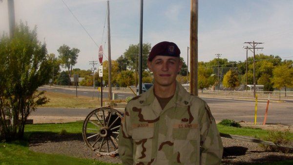 Aaron Jackson in military uniform standing in front of American flag