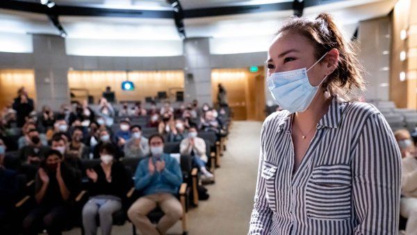 Wei Gordon, Tetrad, makes her way to the stage at Byers Hall to receive first prize at Grad Slam 2022. A crowd cheers in the background.