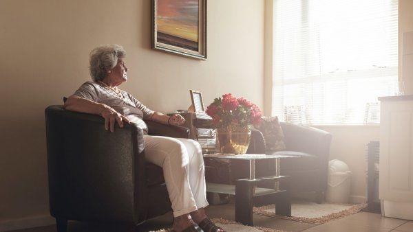 A senior woman sitting alone on a chair at home.