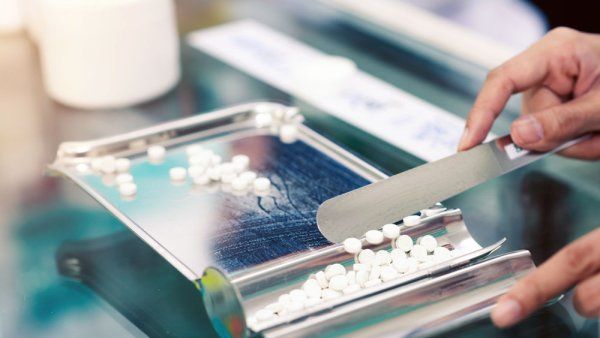 Medicine tablets on counting tray with counting spatula at pharmacy.