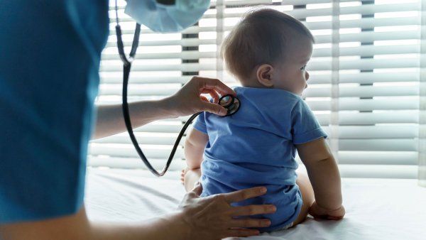 A health professional places a stethoscope to a baby's back