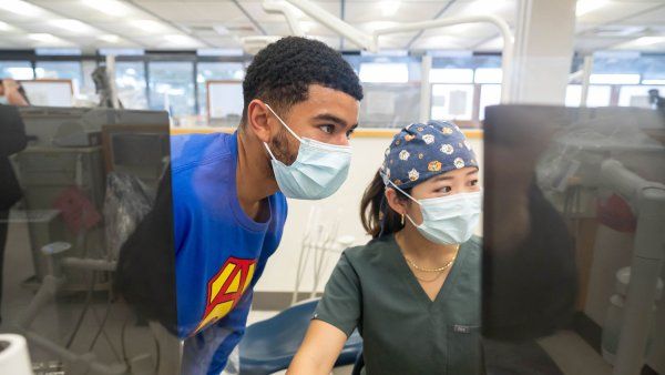 Two dental students look at a computer screen with dental records