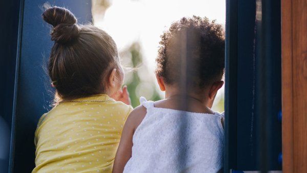 A white toddler and Black toddler sit together at a park