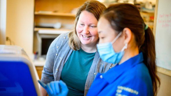 Emily Goldberg speaks with someone in her lab while they point at a screen