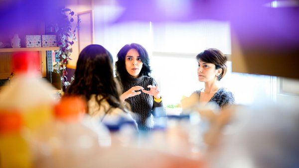 Faranak Fattahi speaks with two female colleagues in her lab. In the foreground is scientific lab equipment