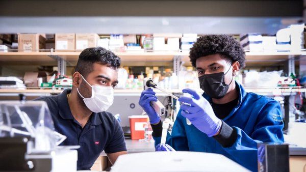 Two men sit in a lab and look at scientific instruments