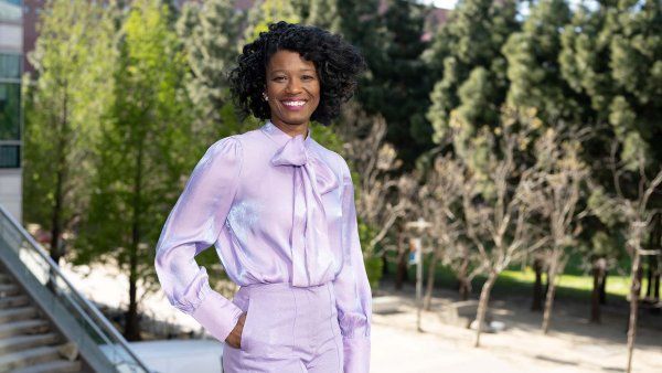 Kai Kennedy stands in front of a bank of trees on UCSF's Mission Bay campus