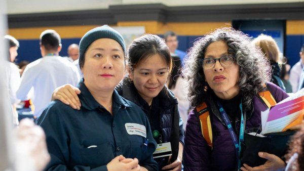 Two UCSF female custodial workers stand with their colleague at Millberry Gym.