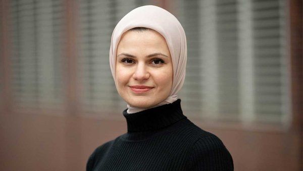 A portrait of Suzanne Barakat. She wears a black turtleneck shirt and a light pink hijab.