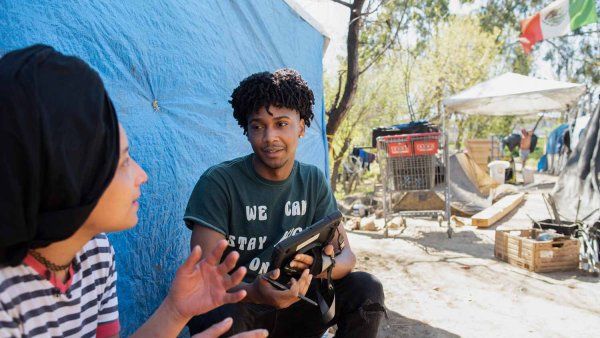 An African-American researcher interviews a woman at a homeless encampment.