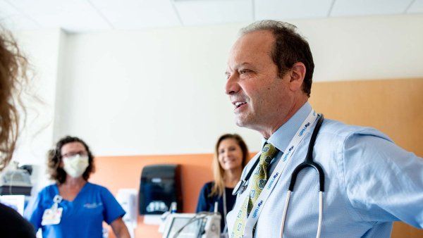 Stephen Gitelman talks with a nurse coordinator and nurse during a patient appointment.