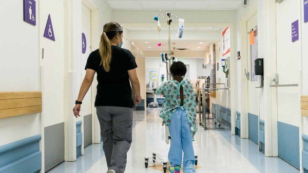 A UCSF staffmember walks with a young patient around the Pediatric Oncology unit at UCSF Childrens Oakland.