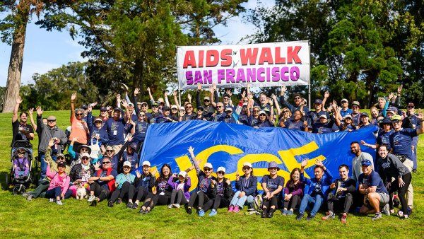 A large crowd of UCSFers poses for a group photo with a sign that reads AIDS Walk San Francisco and a huge UCSF banner