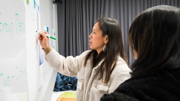 focused asian woman writes on white board