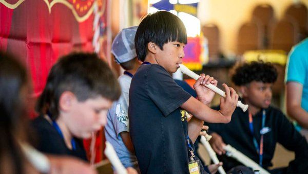 A diverse group of children with limb differences play music on adaptive recorders.