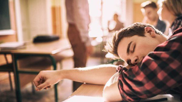 A teenager sleeps on his desk during class.