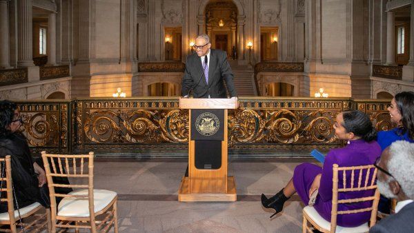 Andre Campbell standing at a podium in City Hall during the ceremony.