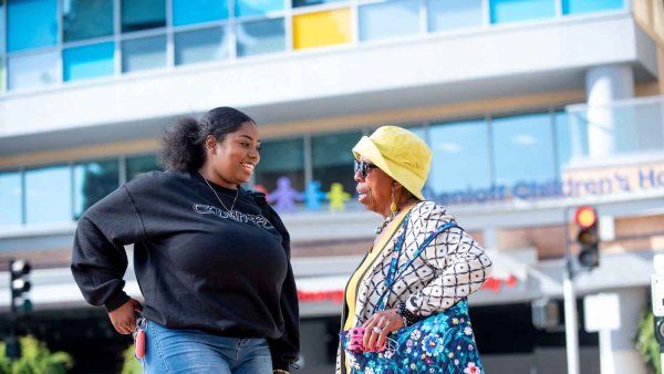 A young African American woman named Brooklyn Haynes and her grandmother cross a street together outside UCSF Benioff Children's Hospital Oakland.