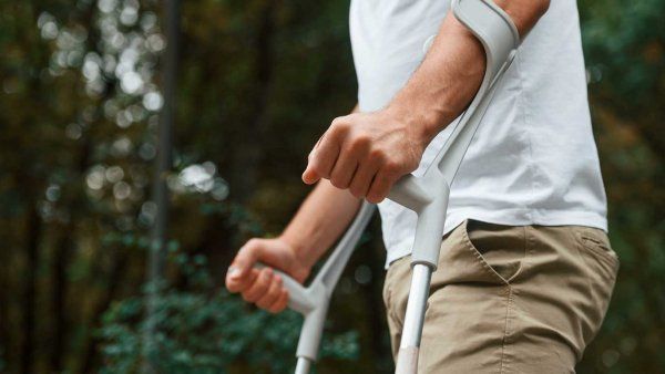 A man walks outside while using crutches for multiple sclerosis.