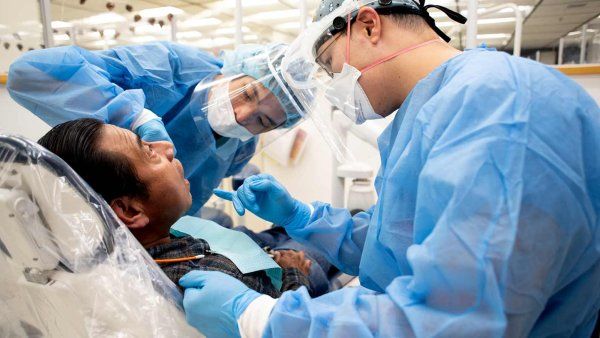 A pair of dentistry students provide dental care to a patient.