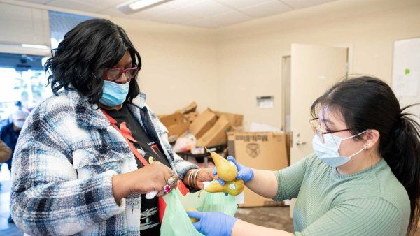 A female patent receives a bag full of fresh produce from a volunteer.