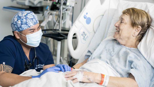 A registered nurse sits at a patient's bedside at Mt. Zion Medical Center.