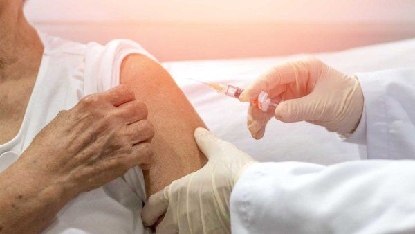 An elderly man receives a vaccine from a doctor.