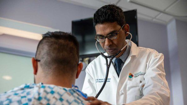 Dr. Anil Makam examines a male patient with a stethoscope at Zuckerberg San Francisco General Hospital.